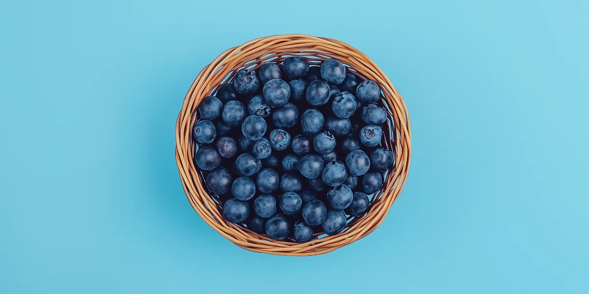 Punnet of seasonal blueberries centered on a blue backdrop