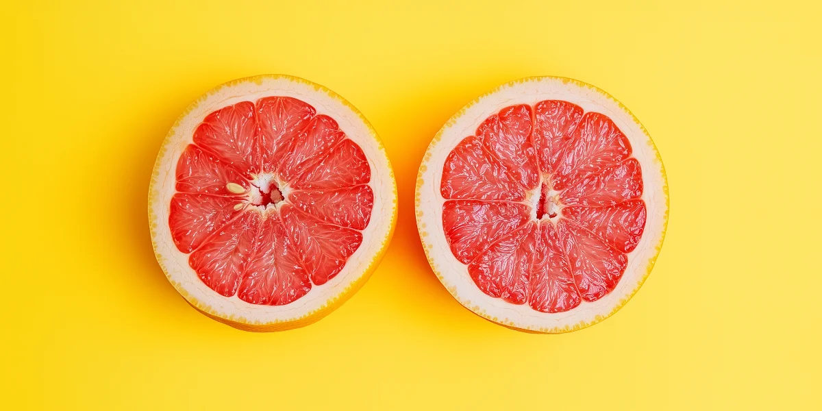 Seasonal ruby grapefruit cut in half and centered on a bright yellow backdrop